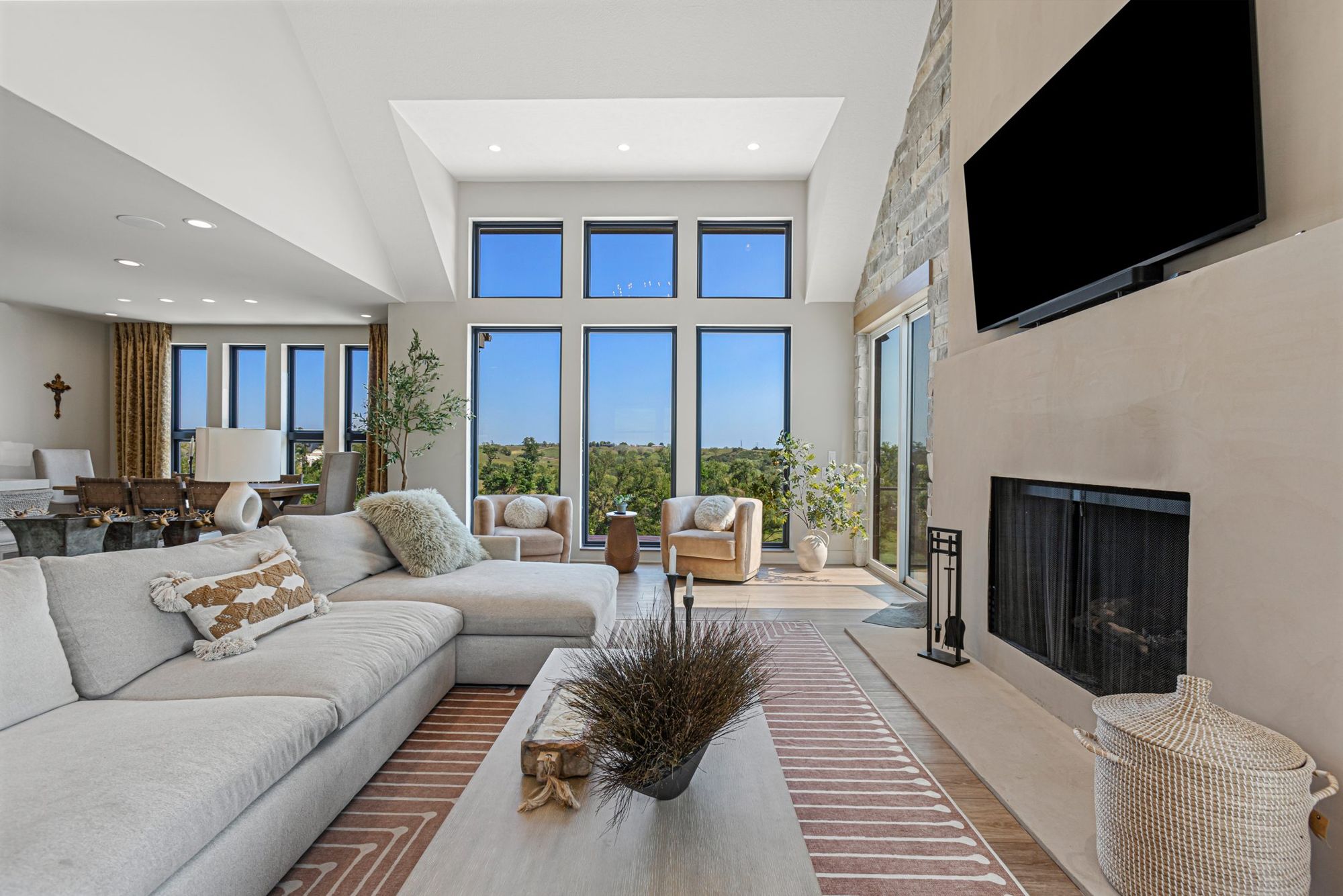 Living room under the vaulted ceiling with a stone fireplace and floor-to-ceiling windows
