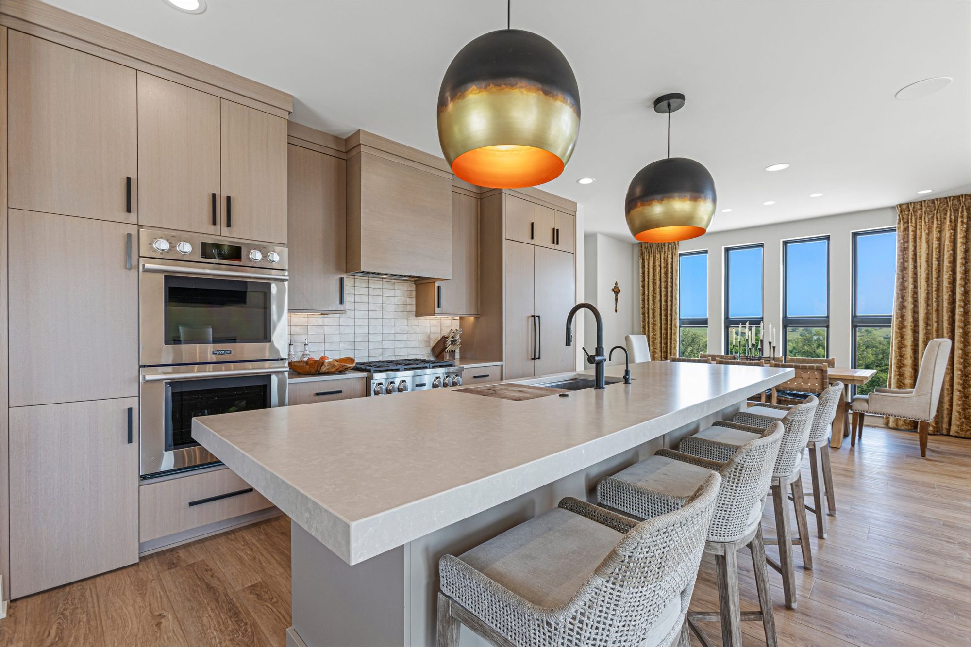 Kitchen island with counter seating under brass-and-black pendants