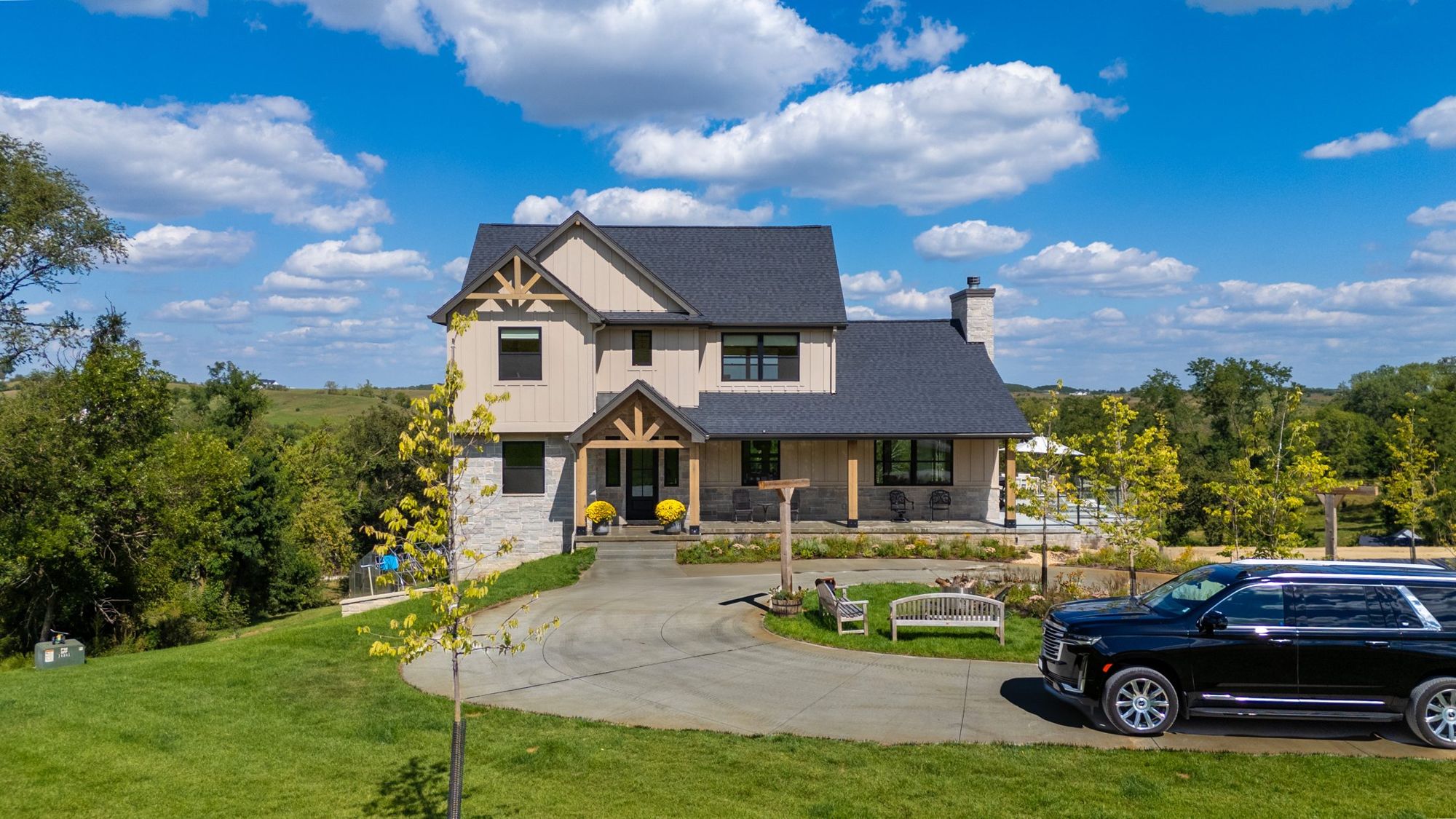 Two-story farmhouse with stone base and timber entry on an acreage