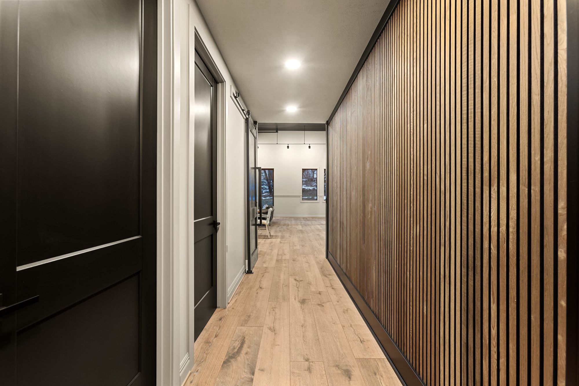 Hallway with black doors and a slatted wood wall