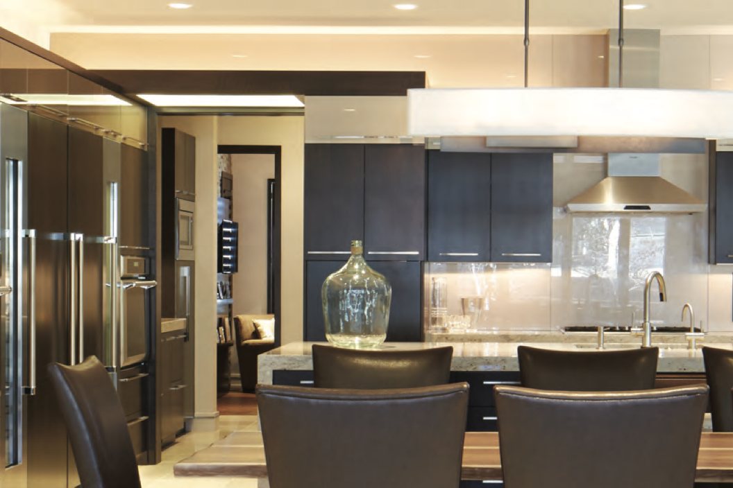 Contemporary kitchen with dark cabinetry, stone island, leather counter stools and a long linear pendant